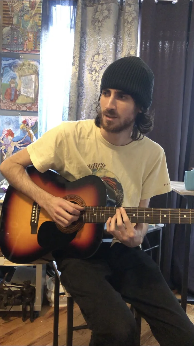 Warren Galea playing acoustic guitar indoors